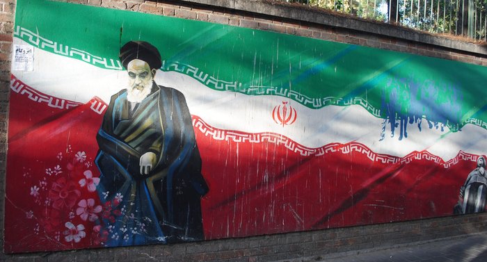 Ayatollah Khomeini with the Iranian flag in the background.